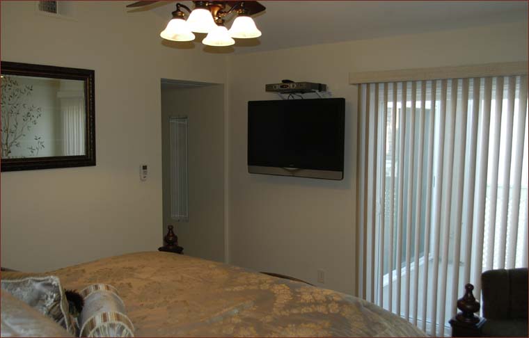 Elegant master bedroom with huge flat screen HDTV and slider to private balcony.